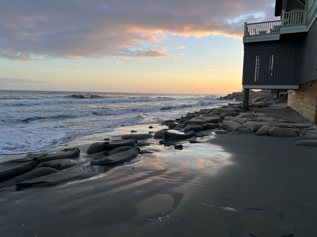 a beach with rocks and a building (MyCoast AI)